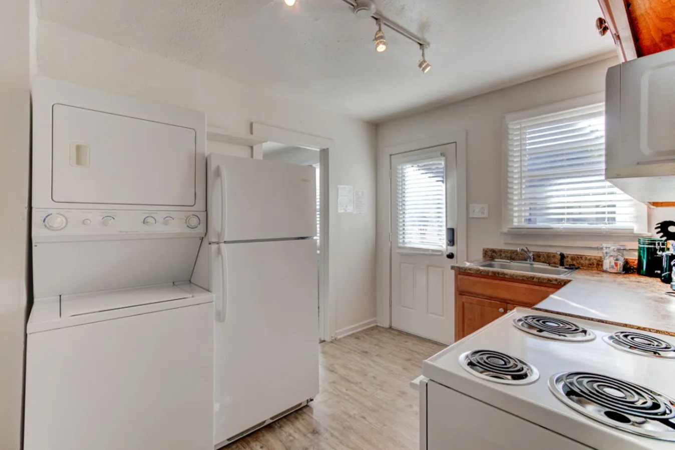 Una cocina compacta con zona de lavandería, refrigerador, lavadora y estufa.