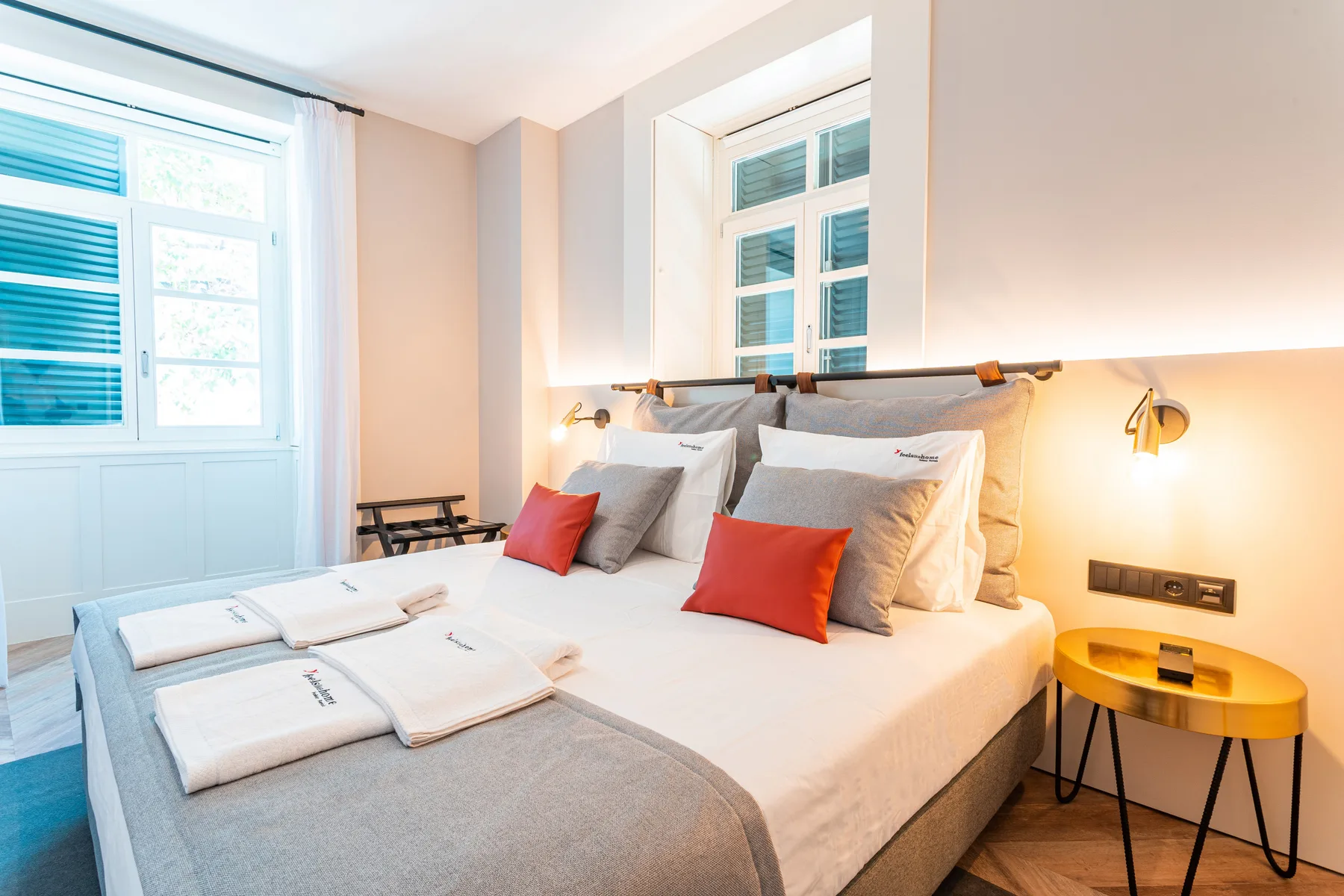 A bright bedroom with a neatly made bed and red accent pillows.