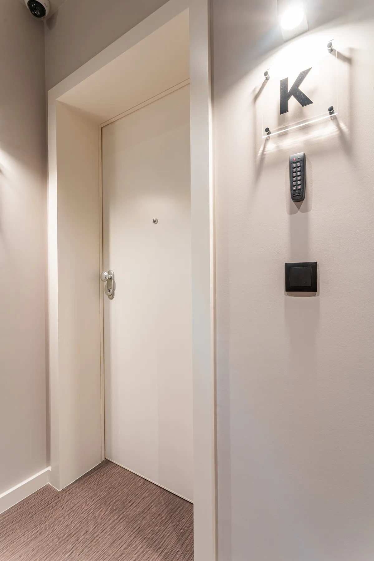 A hallway entrance with a closed door and a wall-mounted keypad.