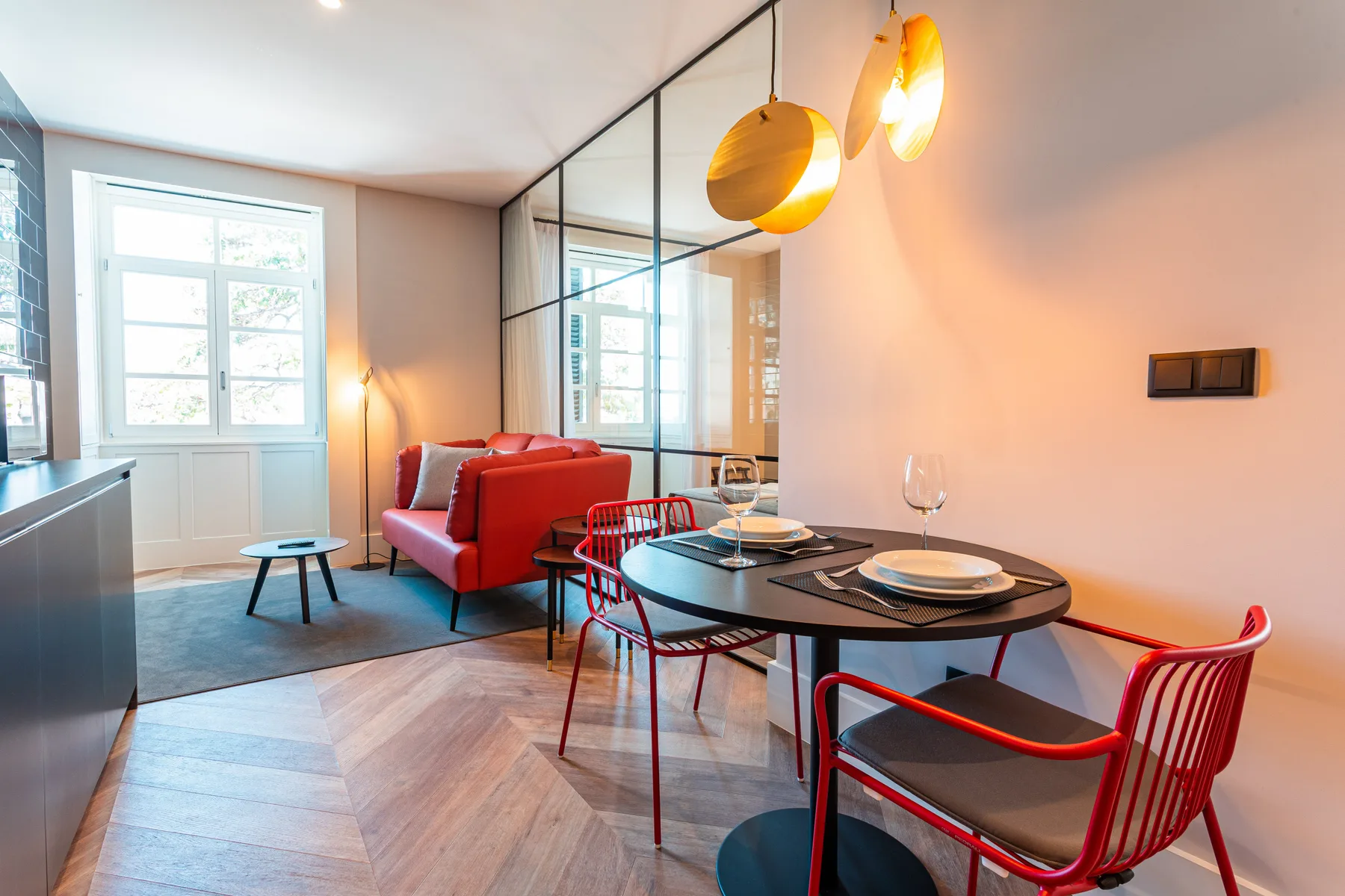 A dining area with a round table and red chairs beside a living area.