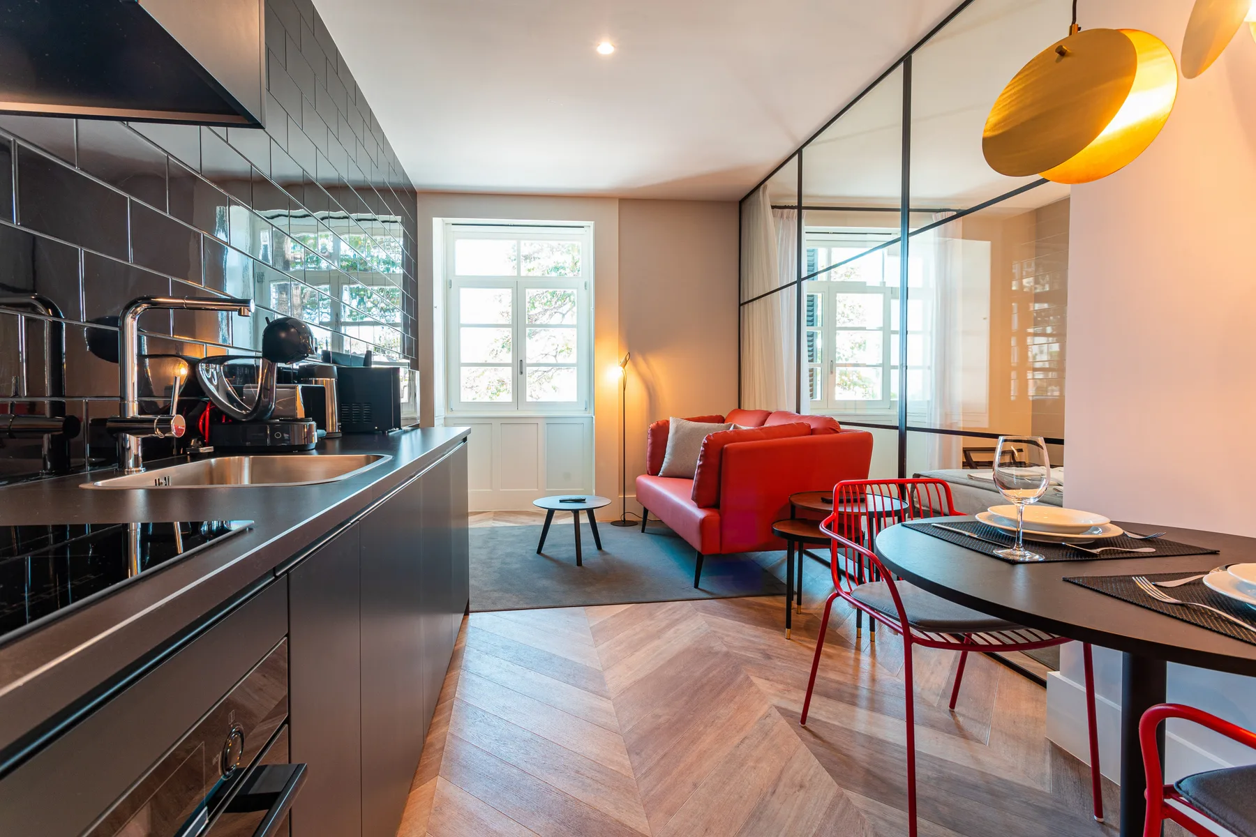 An open-plan living and dining area with a kitchen, red seating, and a round table.