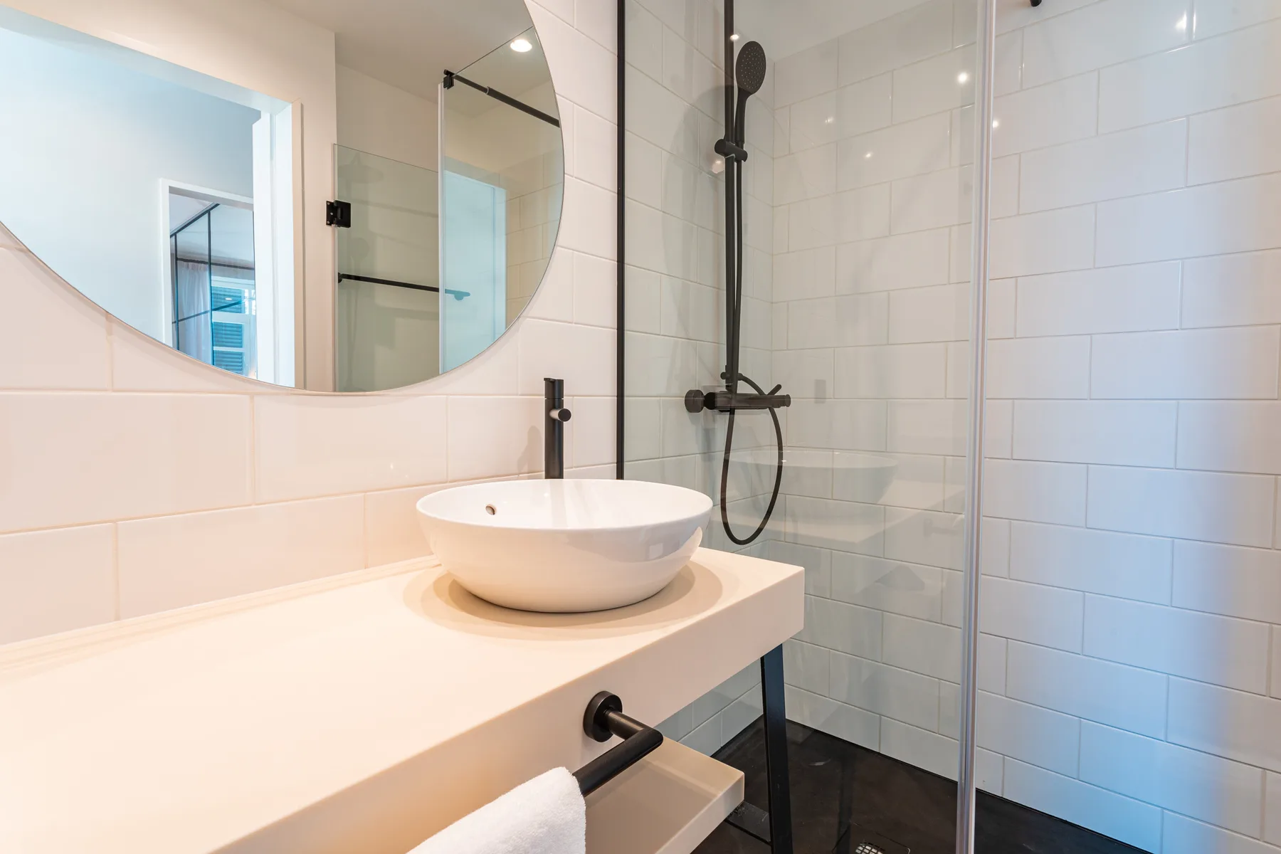 A bright bathroom with a vessel sink and glass-enclosed shower.