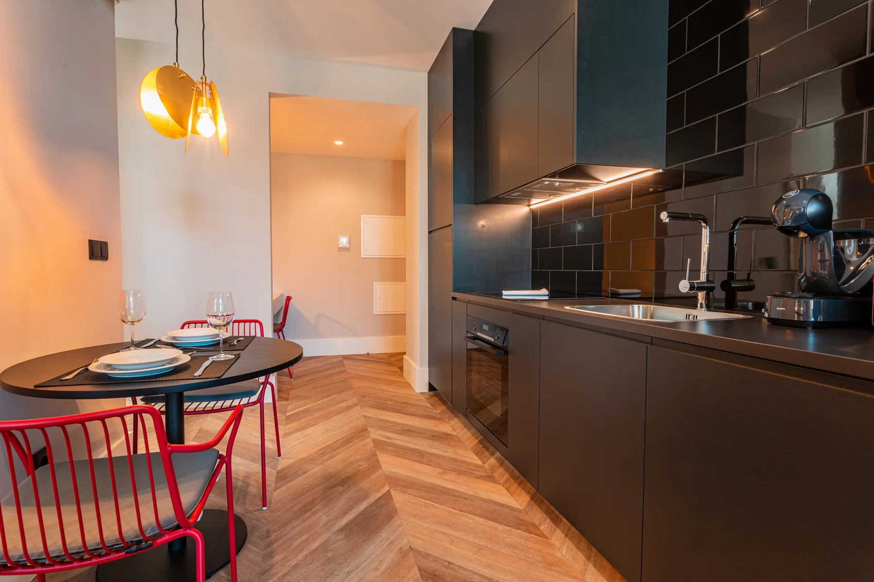 A modern kitchen and dining area with dark cabinetry and a small table.