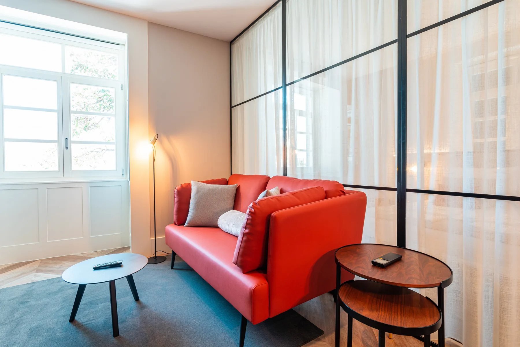 A living room with red seating beside a large window and glass partition.