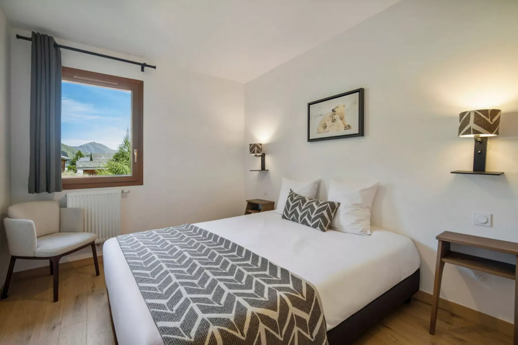 A bedroom with a neatly made bed and a window overlooking the outdoors.