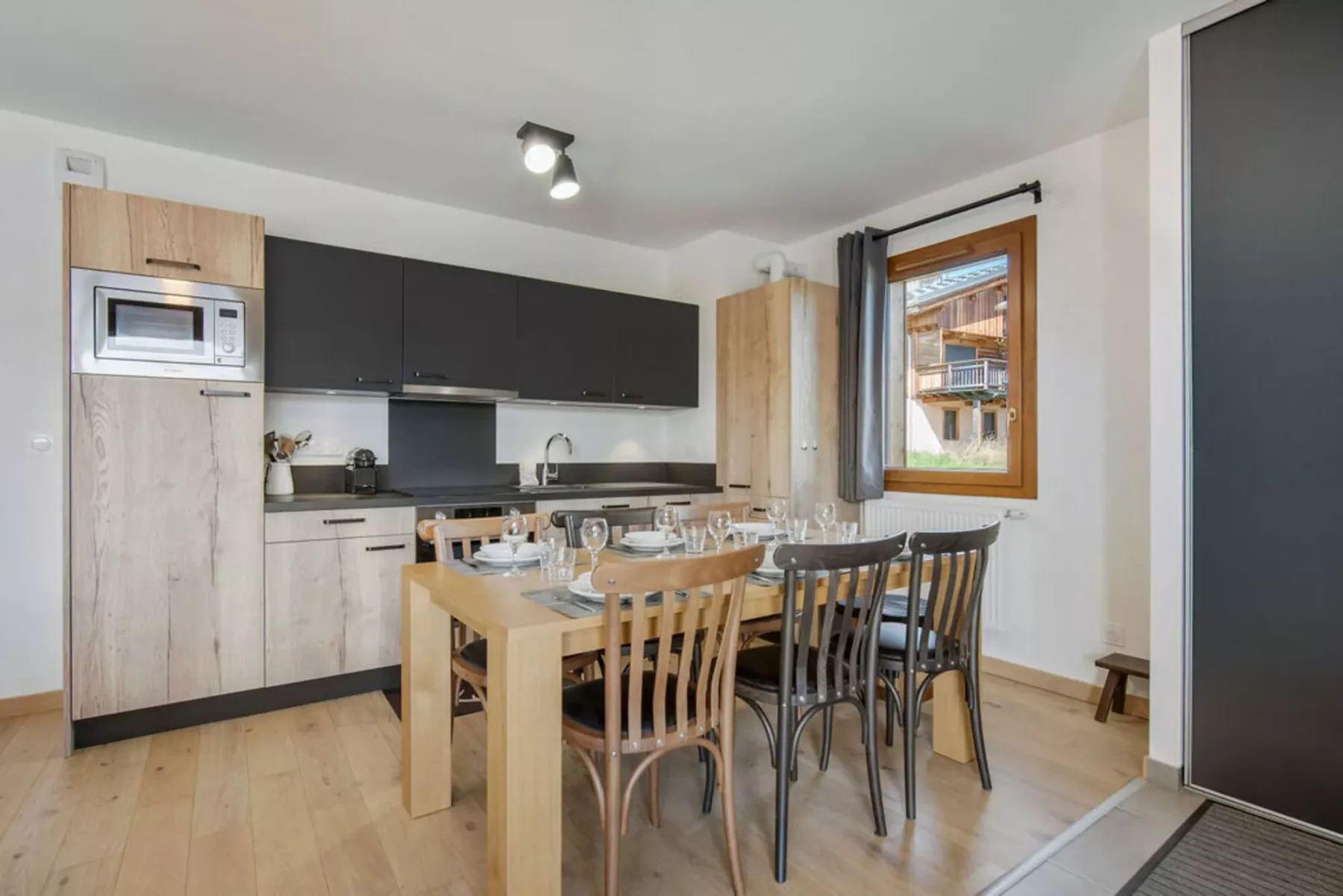 A dining area beside a compact kitchen, with a set table and a window.