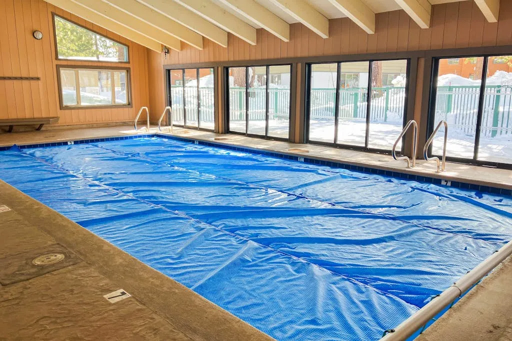An indoor swimming pool is covered by a blue pool cover.