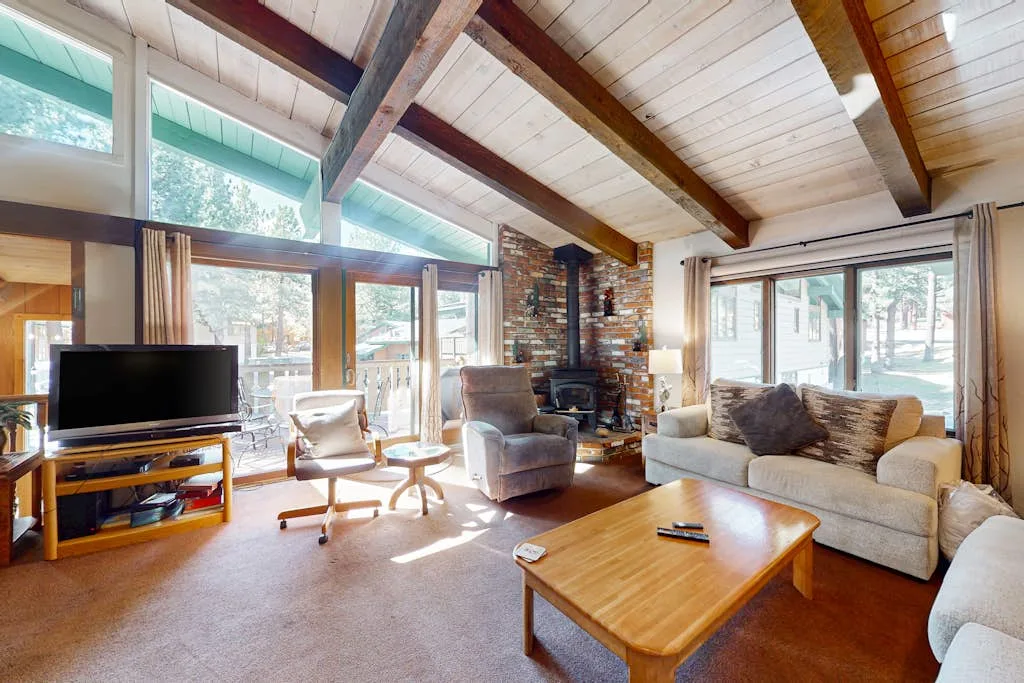 A bright living room has a high wood-beamed ceiling and large windows.