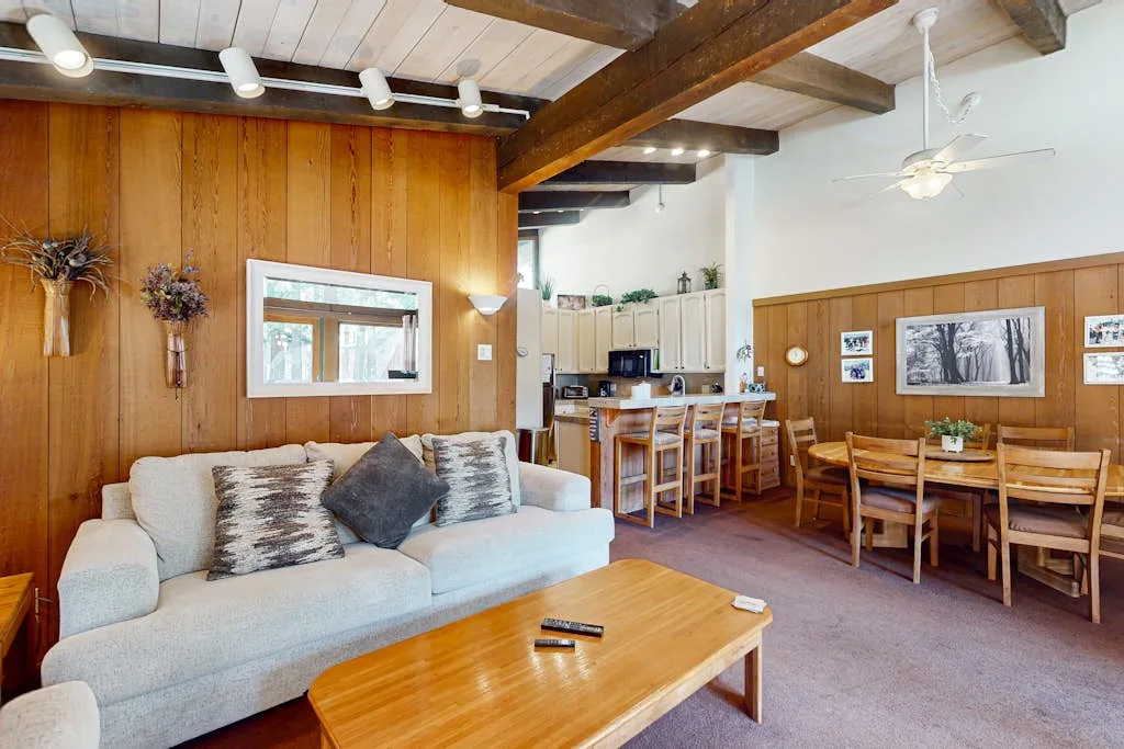 A living and dining area with wood-paneled walls and a light-colored sofa.