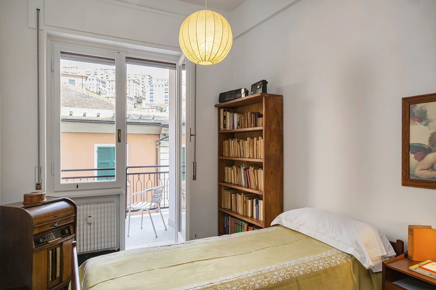 Un dormitorio con una cama, una estantería y puertas de vidrio que dan a un balcón.