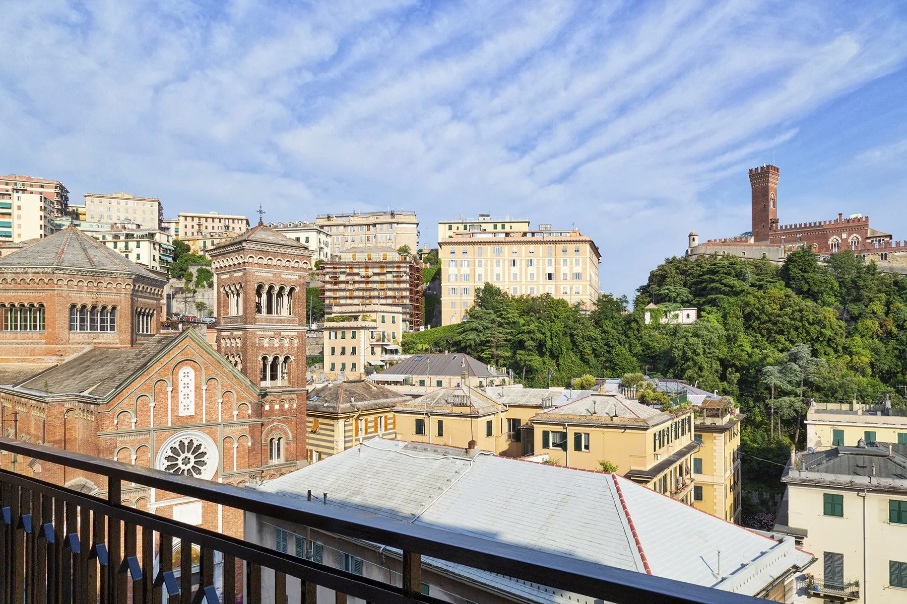 Cityscape with historic brick buildings, hillside greenery, and a tall brick tower.