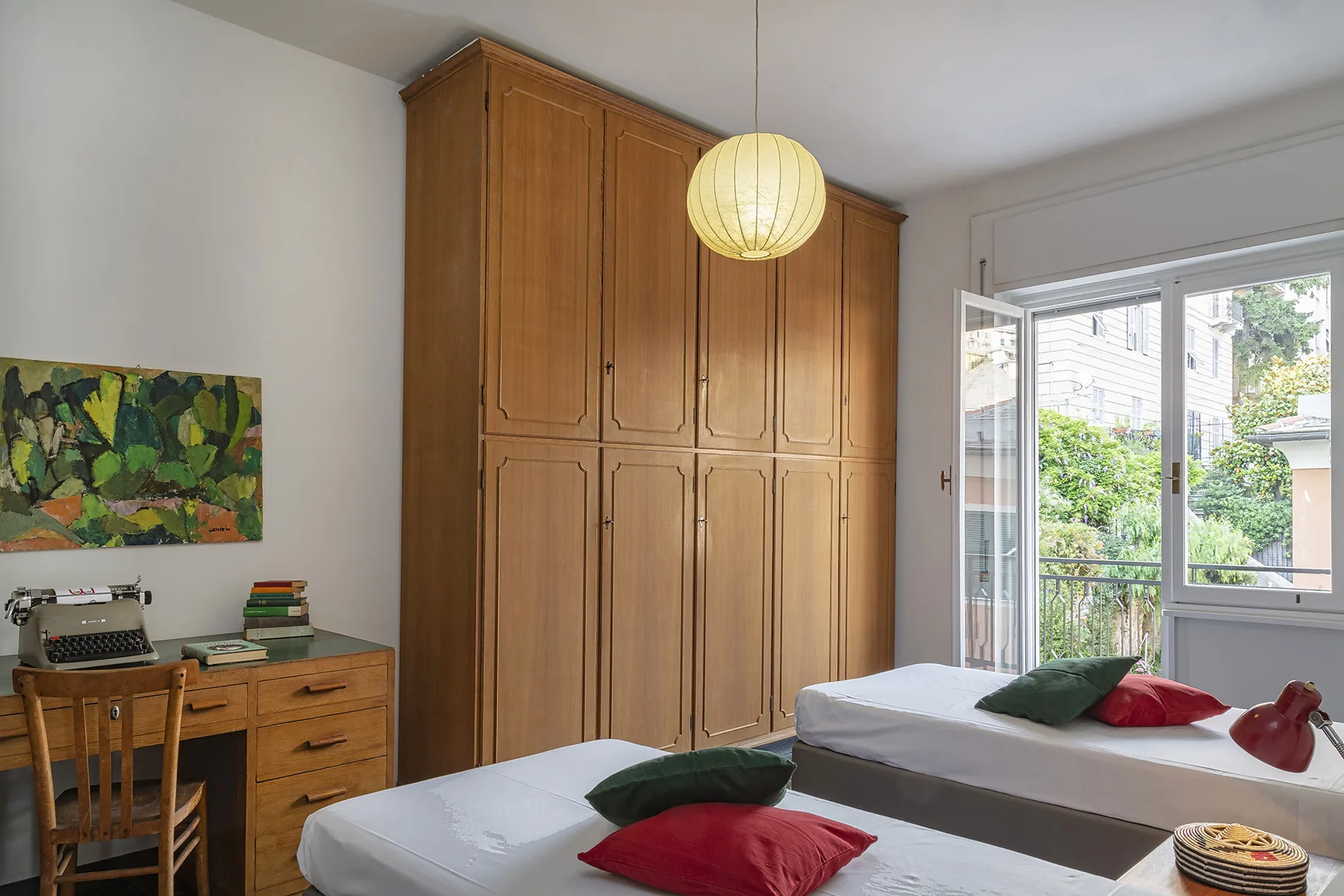 Un dormitorio con dos camas, armarios de madera y una puerta abierta al balcón.