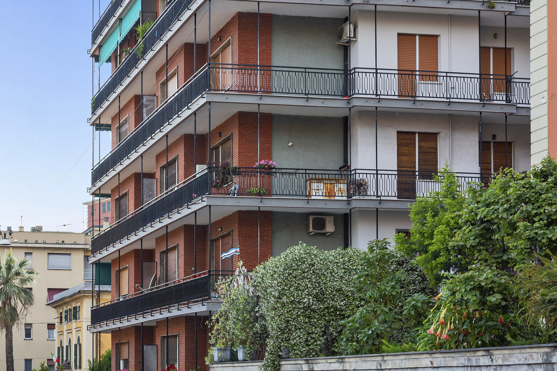 Edificio residencial de varias plantas con balcones y árboles al frente.