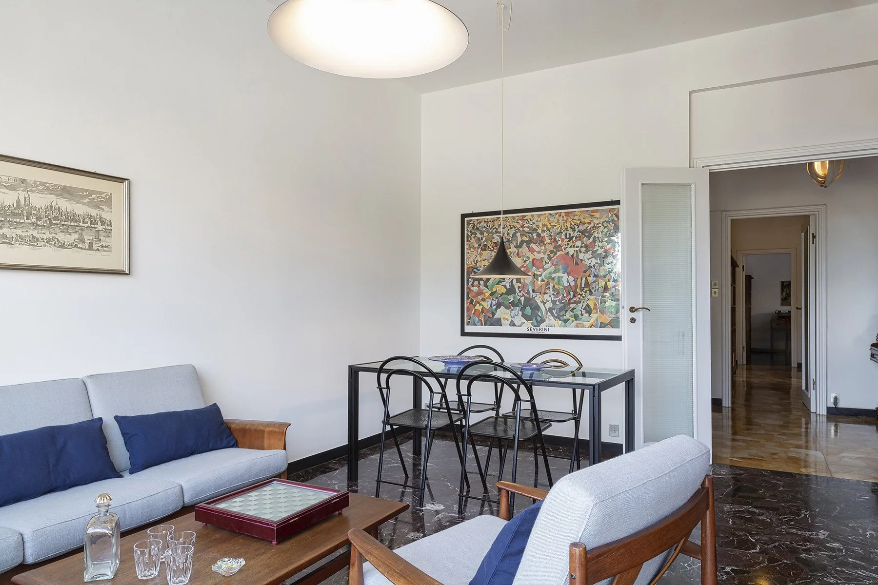 A living and dining area with seating, a table, and colorful framed artwork.