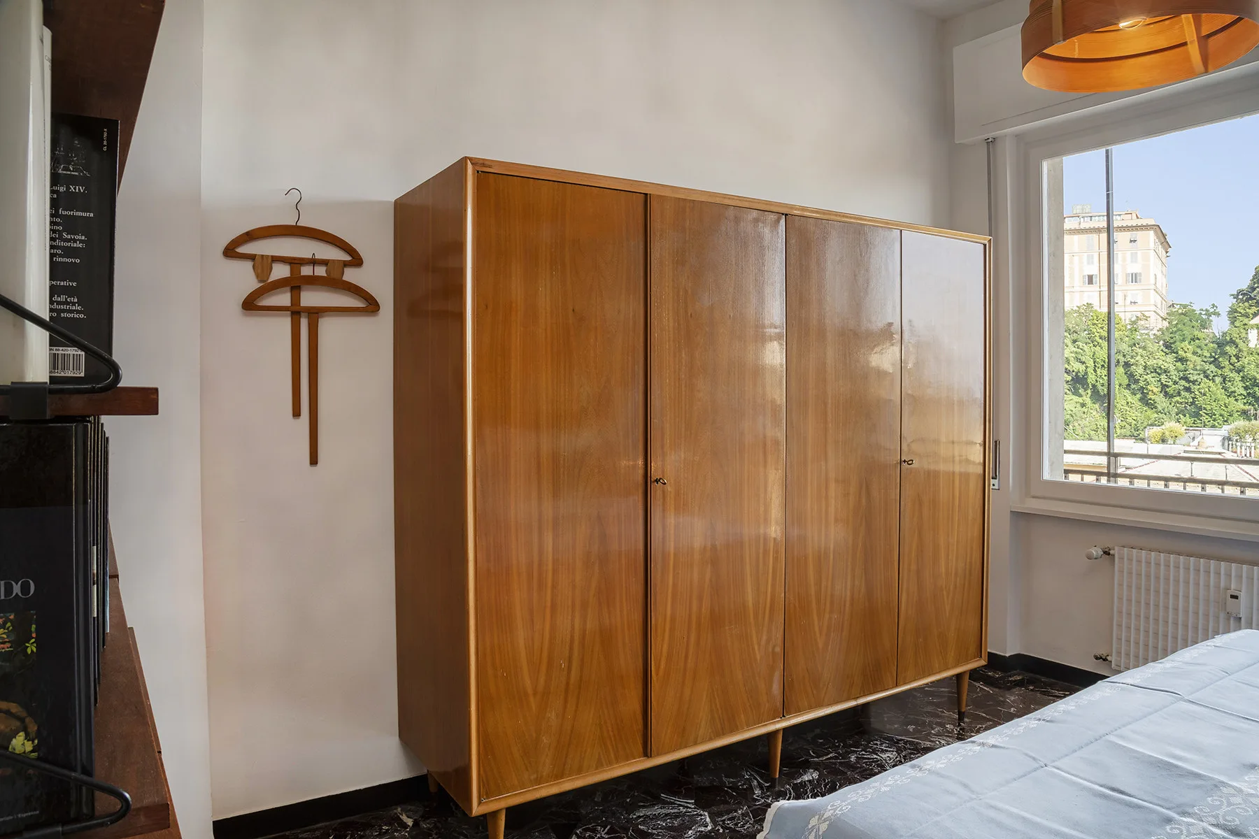 Un dormitorio con un armario de madera junto a una ventana grande.