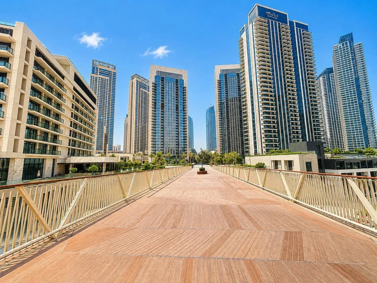 Un puente peatonal conduce hacia un conjunto de edificios modernos de gran altura.
