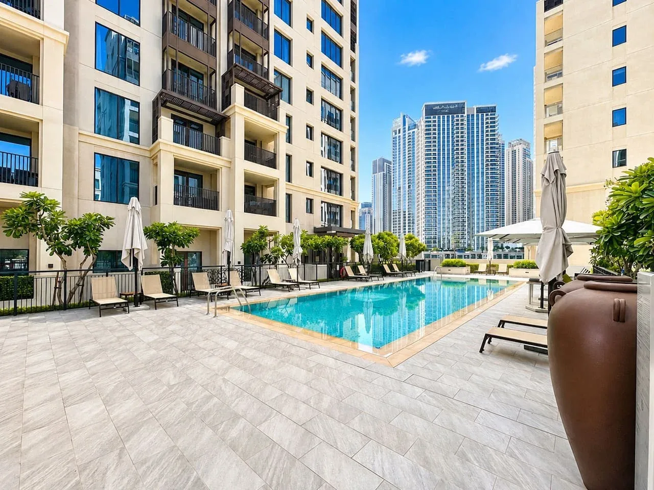 Una piscina al aire libre está rodeada de asientos y edificios altos.