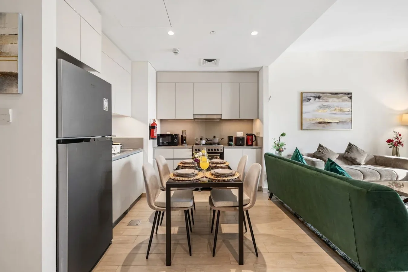 Cocina y comedor de concepto abierto, con un sofá verde junto a la mesa.