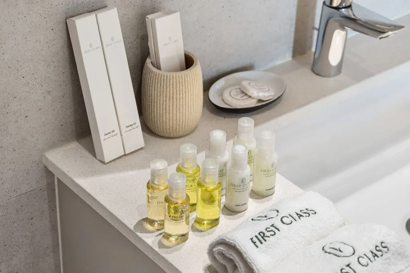 Encimera del baño con artículos de aseo, toallas dobladas y un grifo.