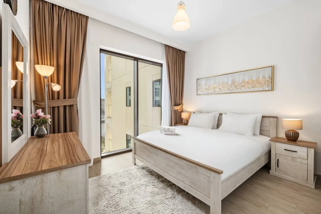 Un dormitorio con una cama grande, mesitas de noche y una puerta corrediza de vidrio.