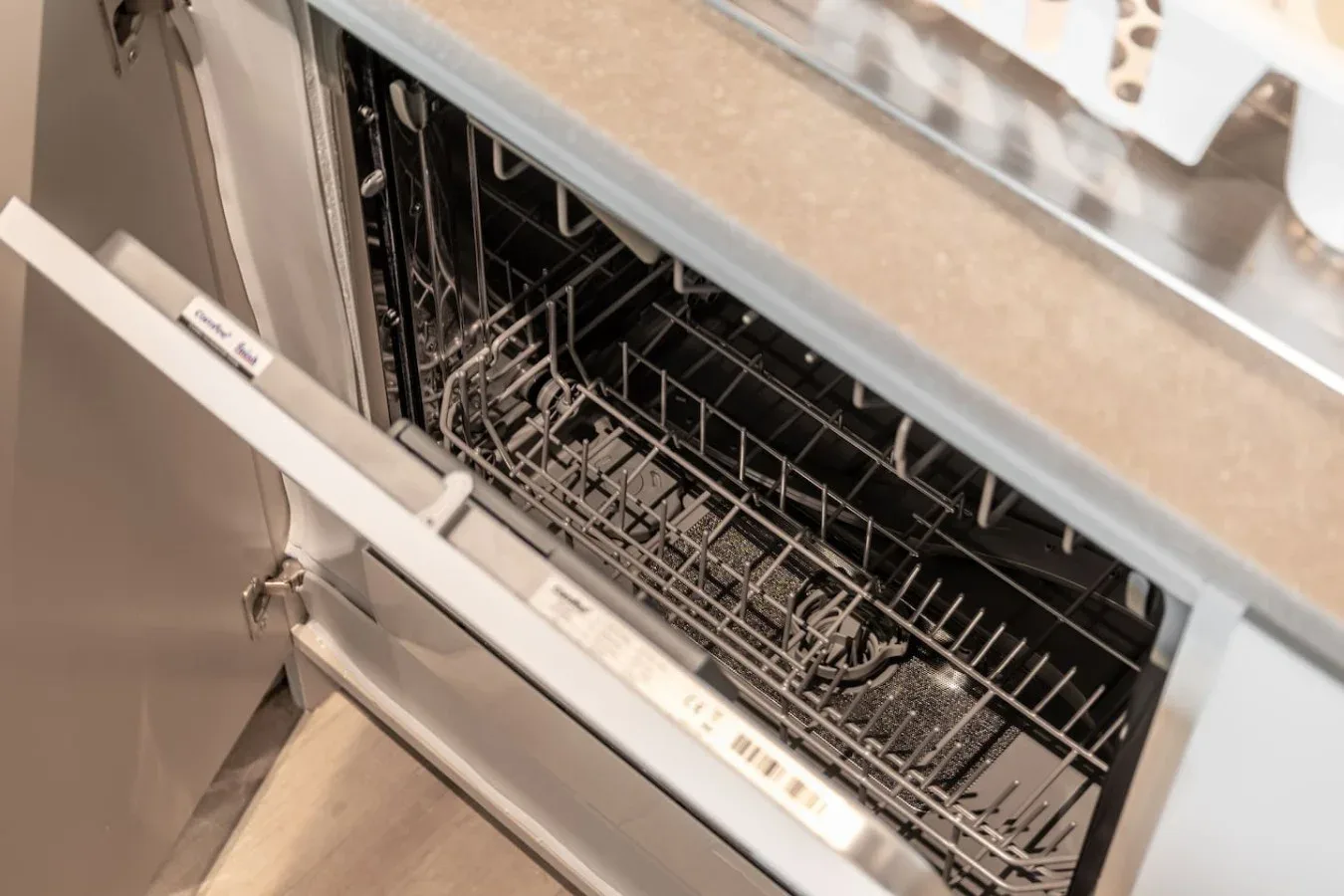 Un lavavajillas está abierto debajo de una encimera de cocina.