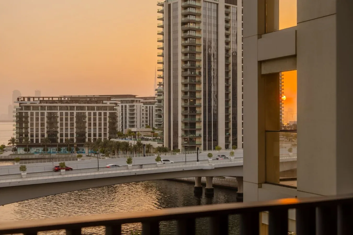 Edificios altos dan a un canal y un puente con la cálida luz del atardecer.
