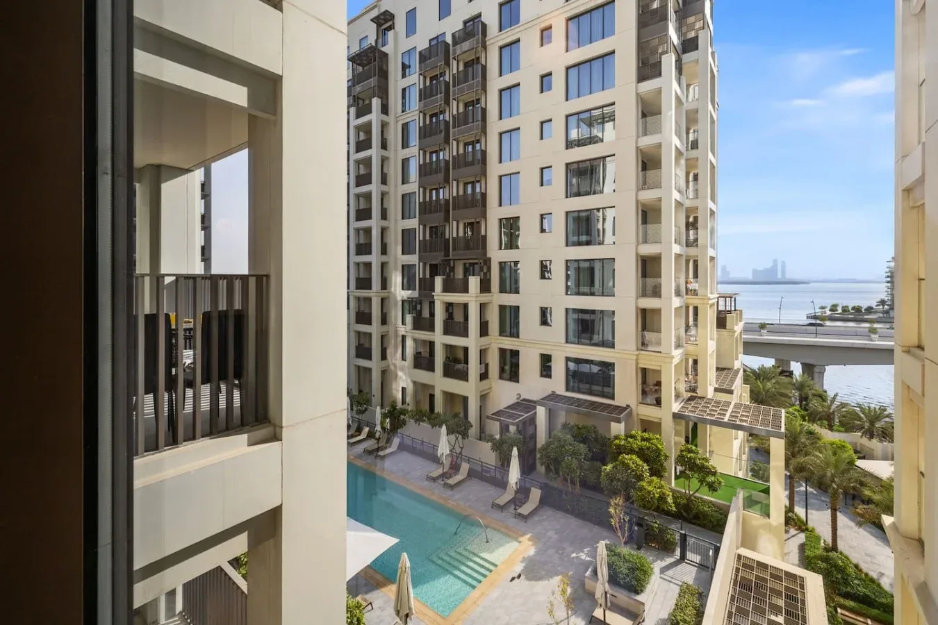 Un edificio residencial da a una piscina al aire libre y un patio ajardinado.