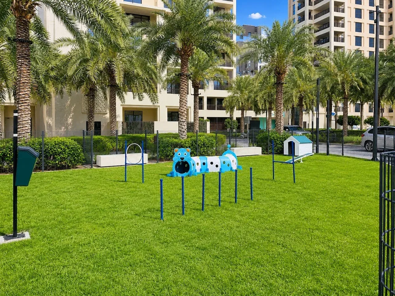 Una zona de juegos al aire libre con césped, estructuras coloridas para trepar y palmeras.
