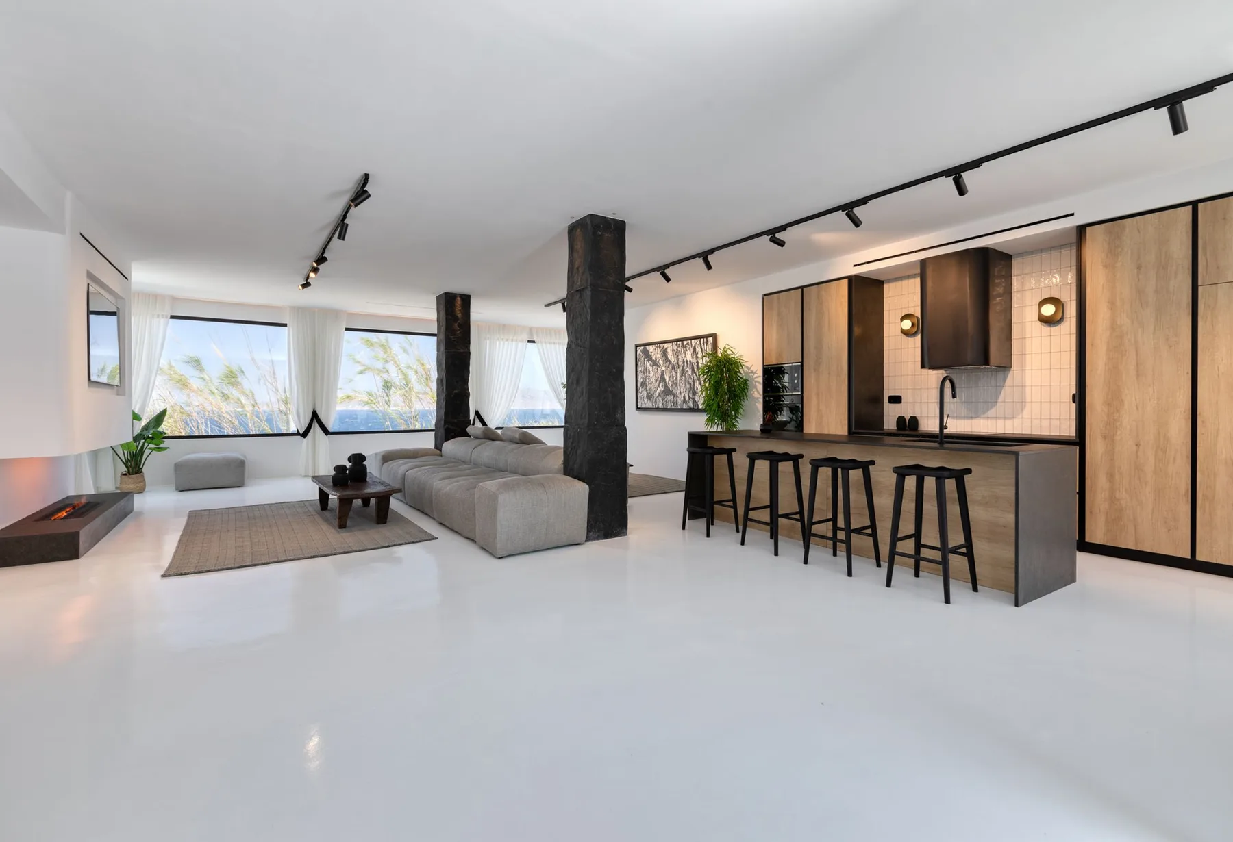 Open-plan living area with seating beside a kitchen island and bar stools.