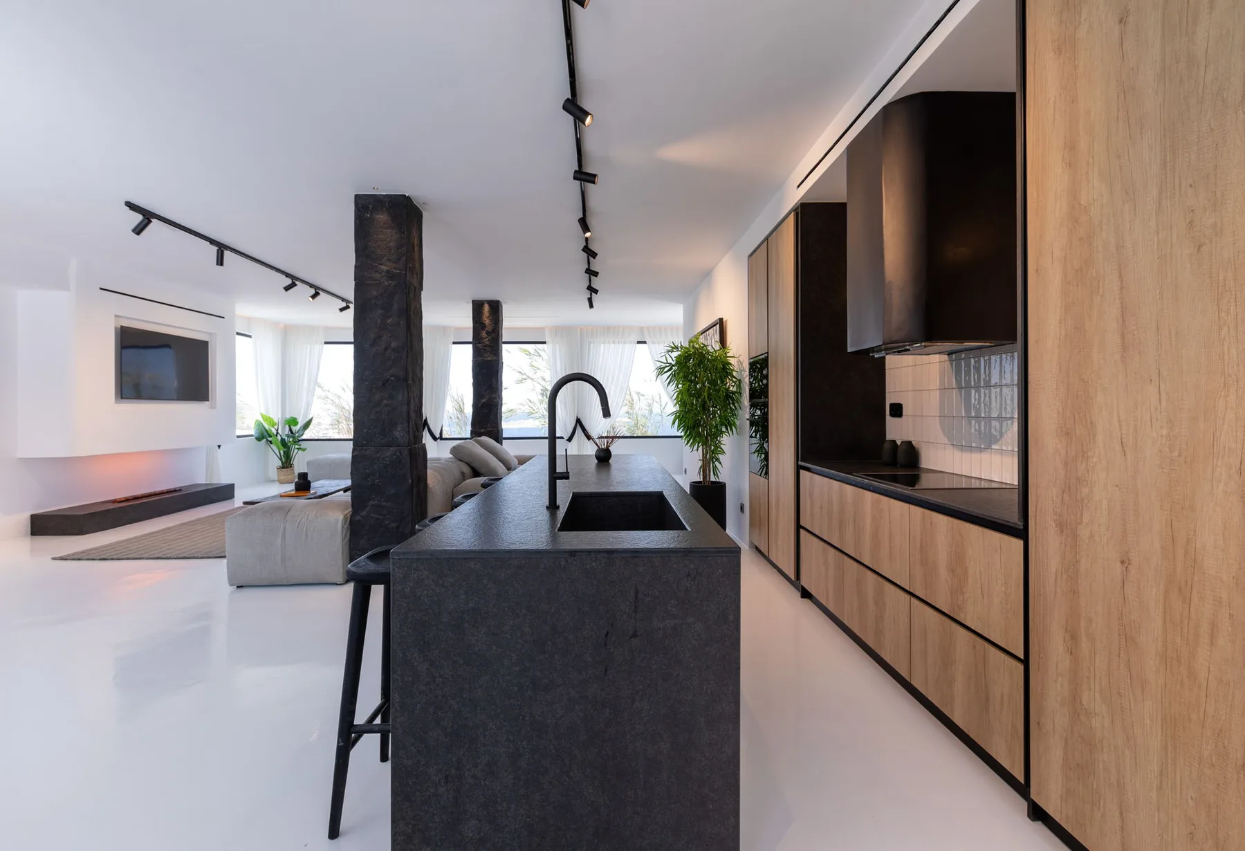 Cocina y sala de estar de planta abierta, con una isla oscura y armarios integrados.