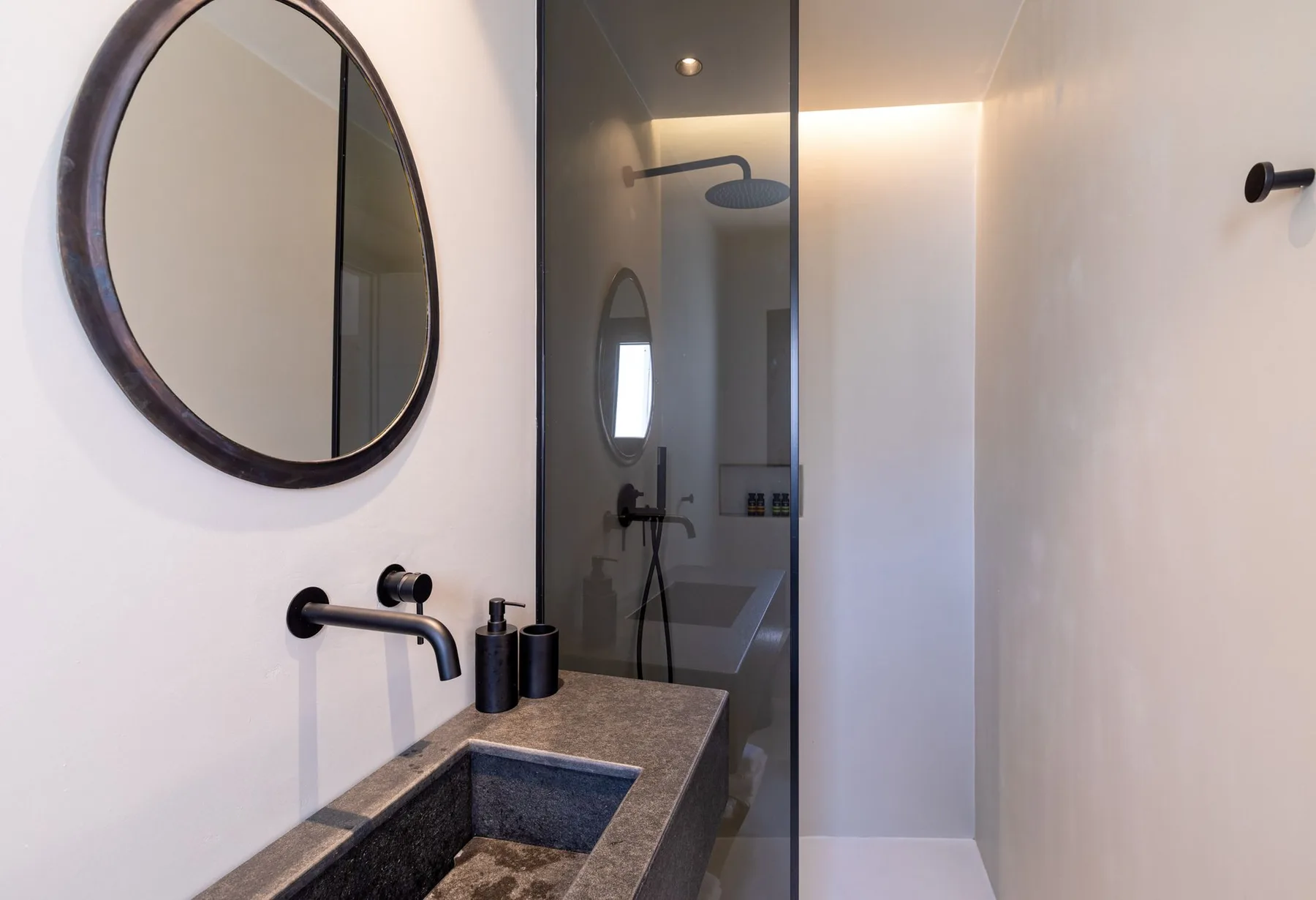 Un baño moderno con lavabo de piedra oscura y ducha de cristal.