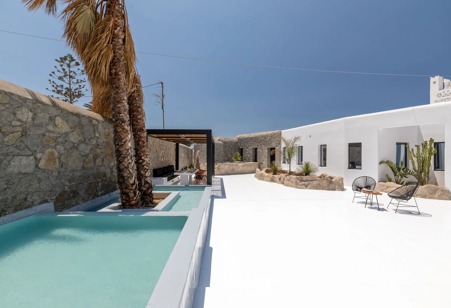 A white villa courtyard with a swimming pool and outdoor seating.