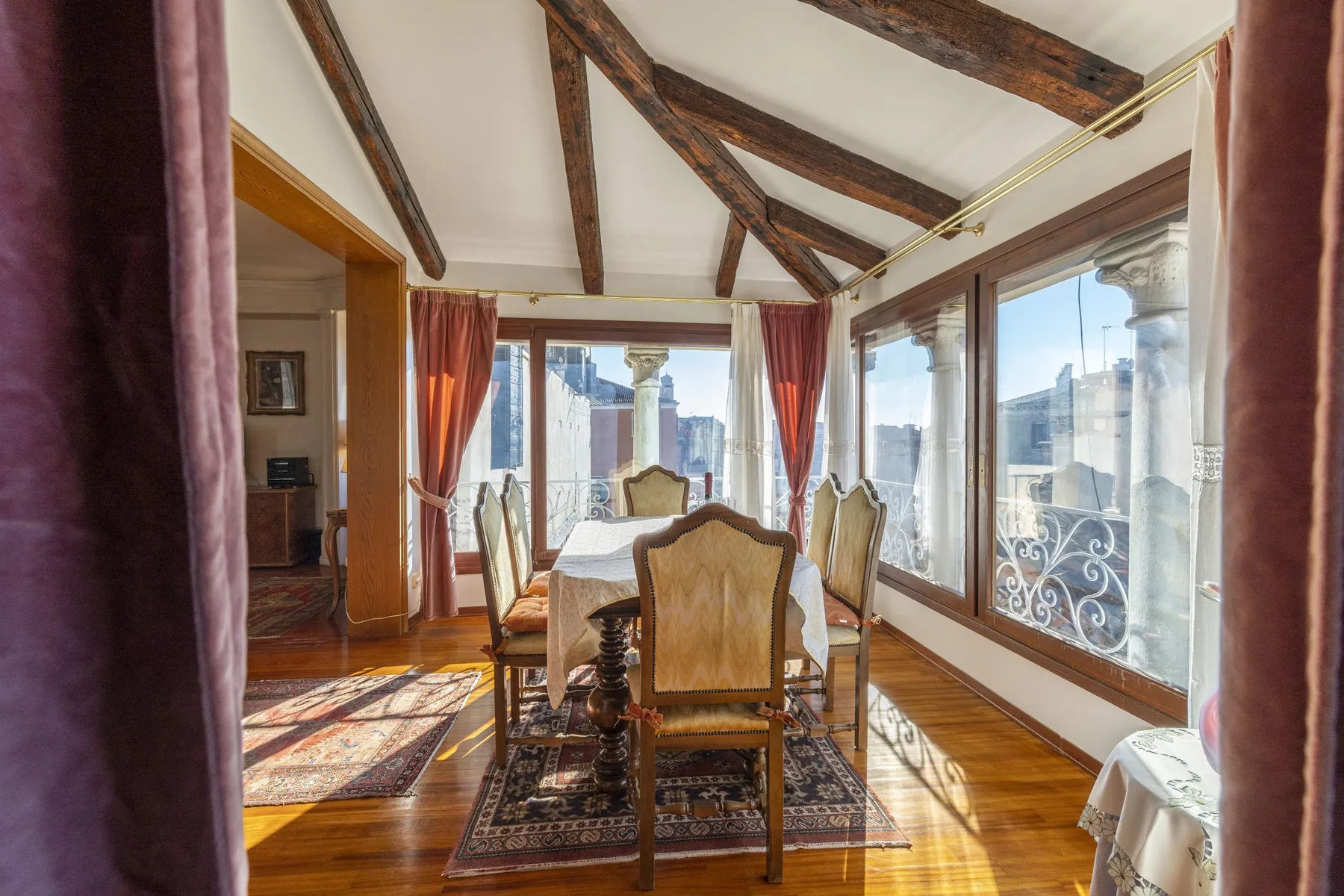 A dining area with a table and chairs beneath exposed wooden ceiling beams.
