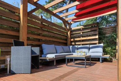A covered outdoor seating area with a sectional and low table.