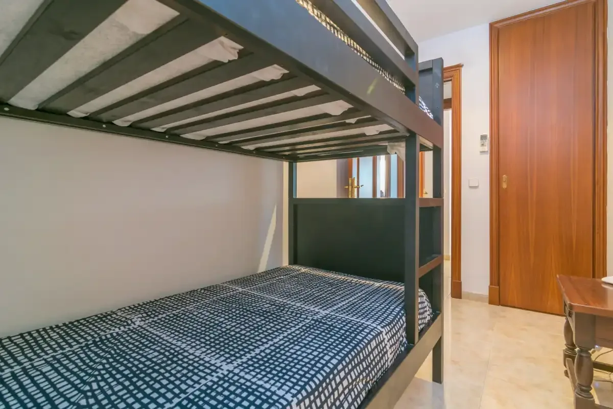 Un dormitorio con una litera y una puerta de madera.