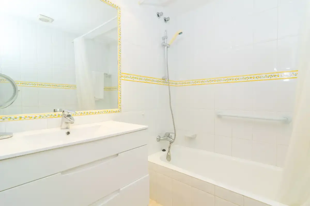 Un baño luminoso con bañera, ducha y lavabo.