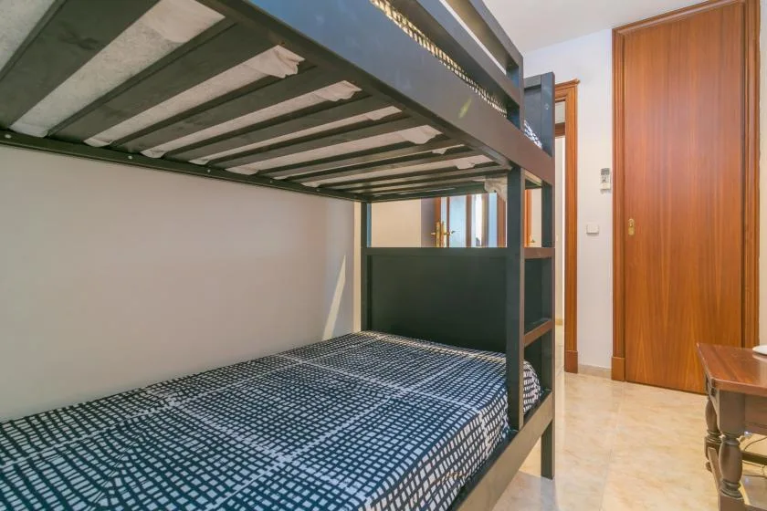 Un dormitorio con una litera oscura y una puerta de madera.