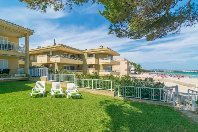 Un edificio de apartamentos junto a la playa da a un césped y al mar.