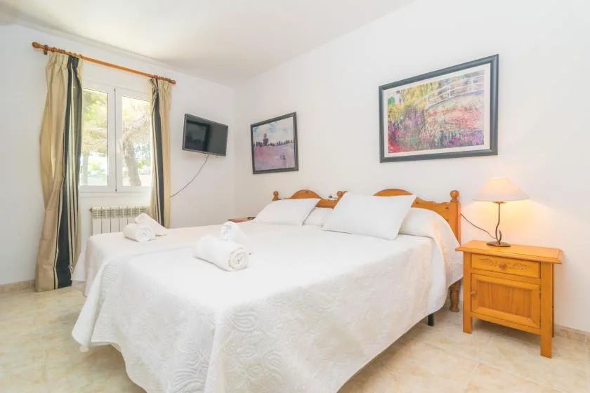 Un dormitorio luminoso con una cama grande, cuadros enmarcados y una mesita de noche.