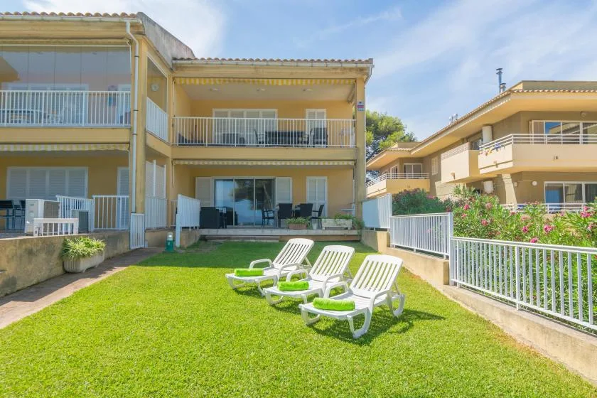 A grassy courtyard with white lounge seating between apartment buildings.