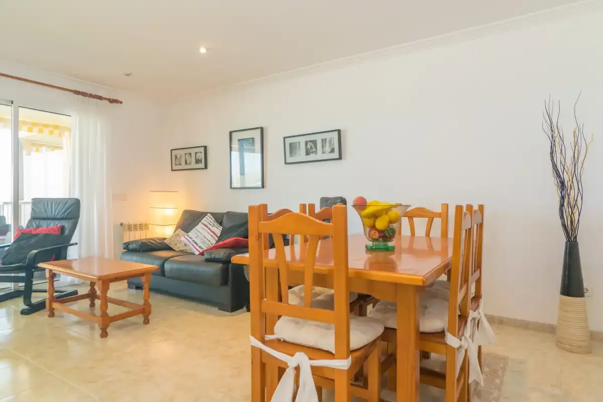 Una zona de comedor y estar con una mesa de madera y asientos.