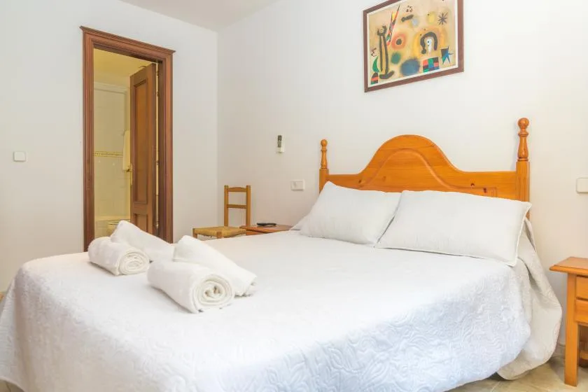 Un dormitorio con una cama bien hecha y un cuadro enmarcado sobre el cabecero.