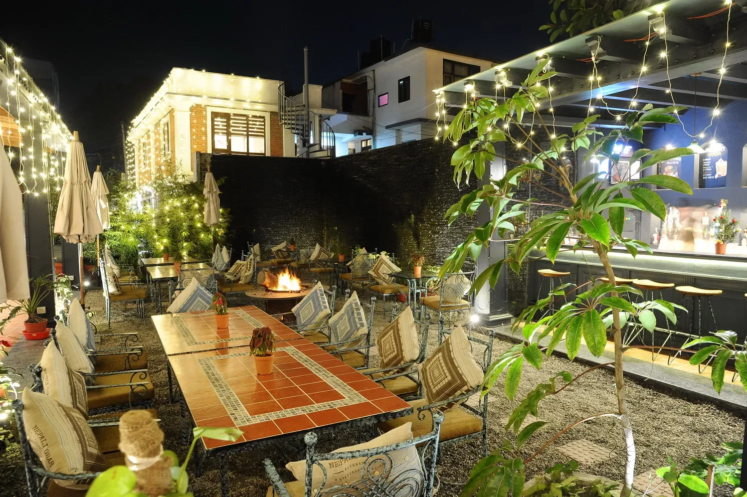 Garden courtyard table and fire pit beneath string lights.
