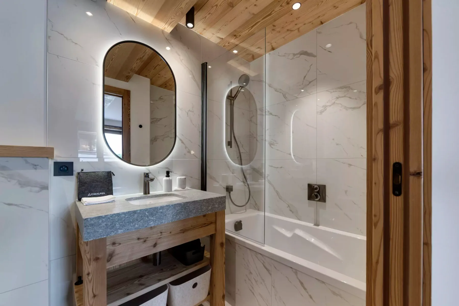 Un baño con lavabo, espejo ovalado y bañera con ducha de mano.