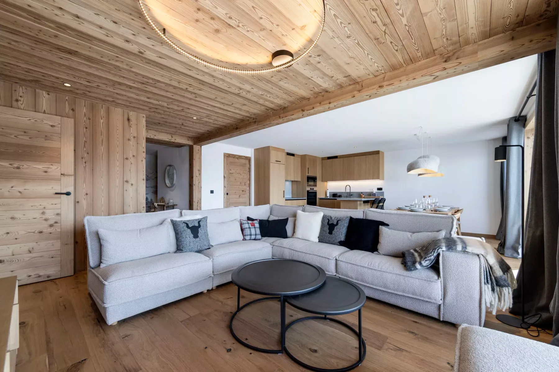 A bright living room with a large sectional seating area and an open kitchen.