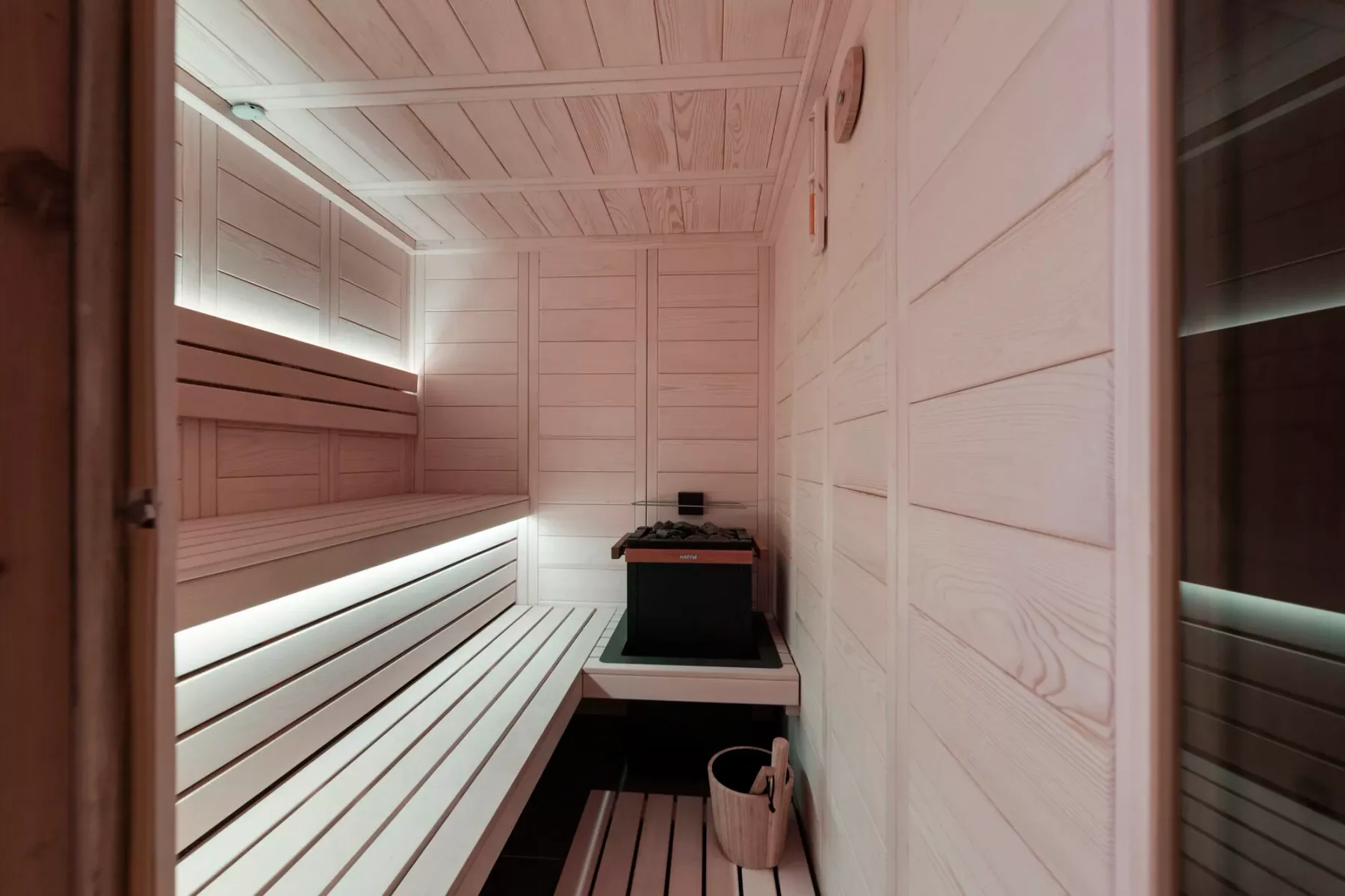 Una sauna revestida de madera, con asientos escalonados y un calentador.