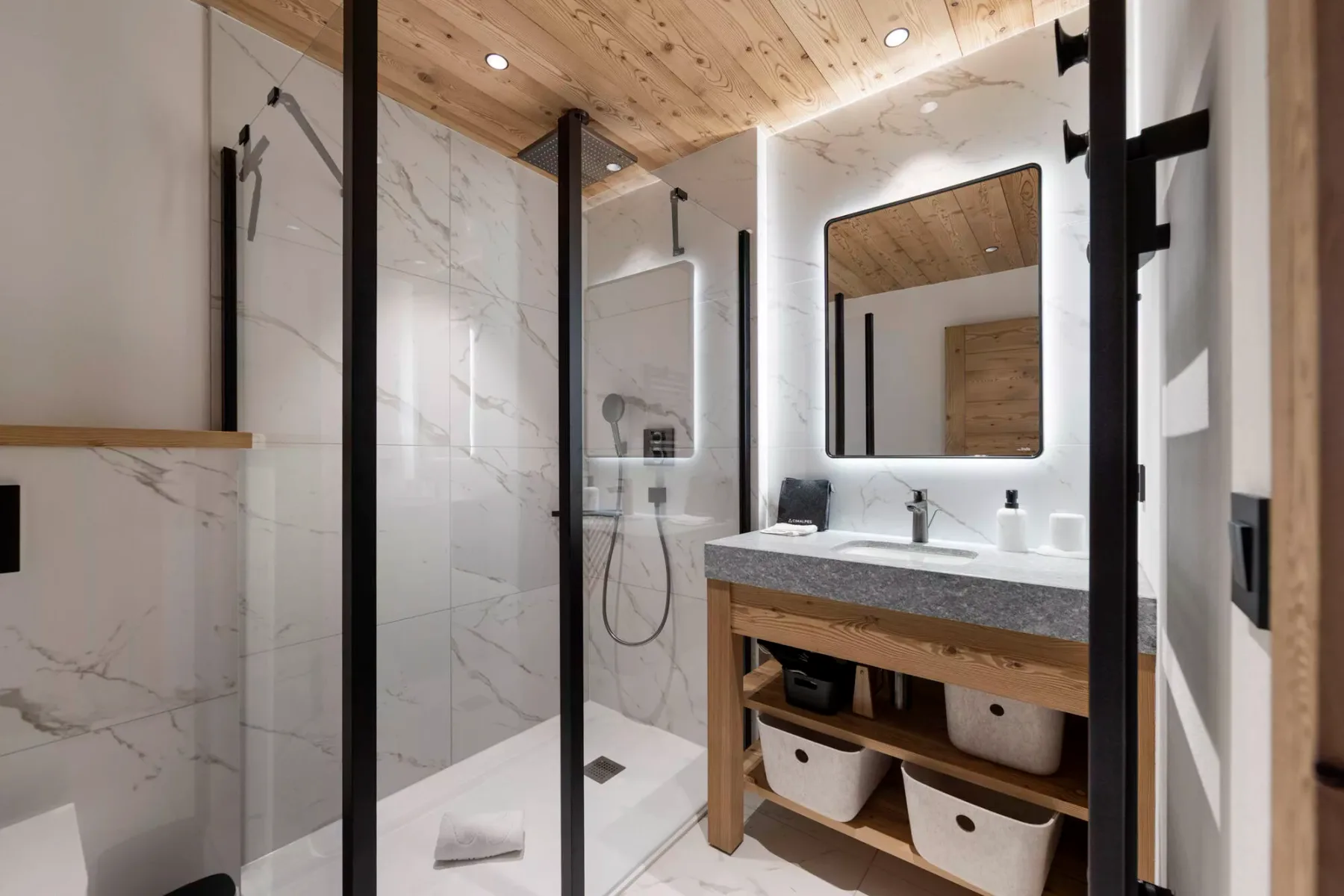 Un baño moderno con ducha de vidrio y un mueble de lavabo de madera.