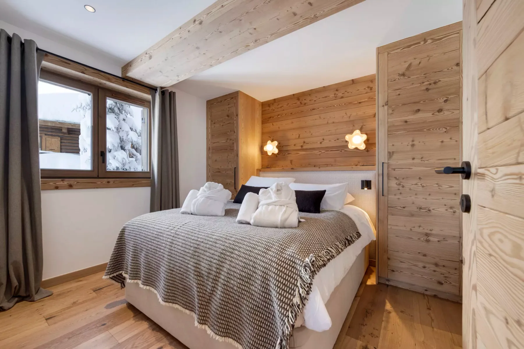 Un dormitorio con una cama, paredes de madera y una ventana.