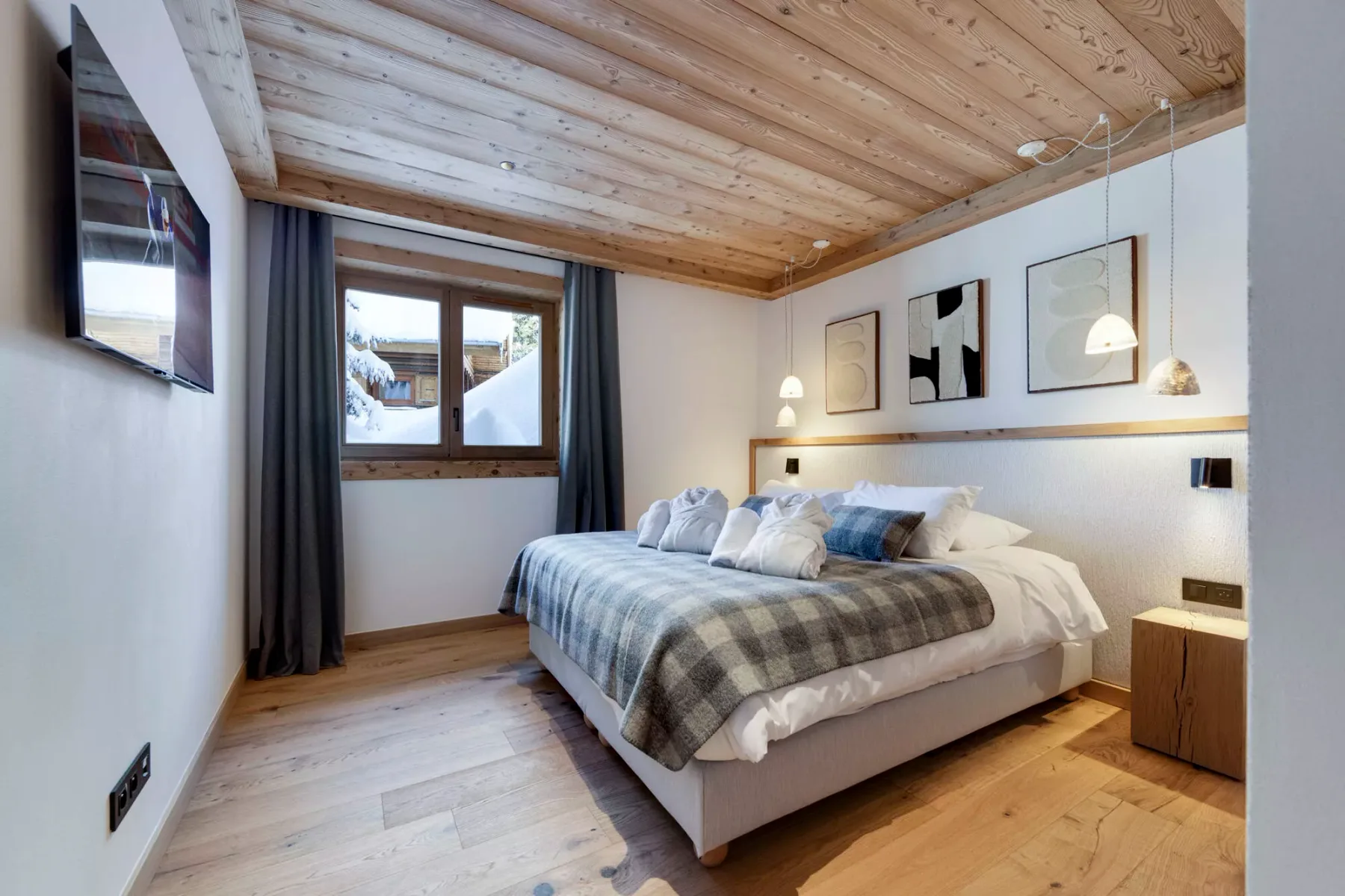 Un dormitorio con una cama, una ventana y un techo de madera clara.