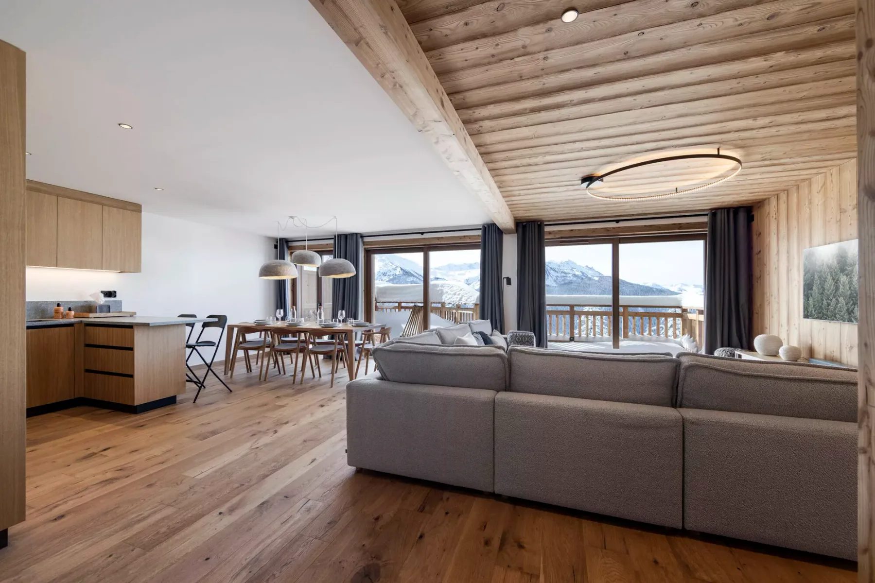 An open-plan living and dining area with seating beside large windows overlooking the mountains.